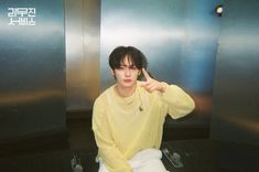 a young man sitting on top of a toilet in a bathroom next to two urinals