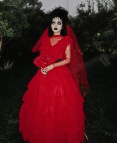 a woman in a red dress with black makeup and white make - up on her face