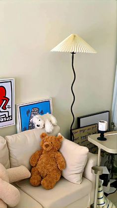 two teddy bears sitting on a couch in front of a table with pictures and a lamp