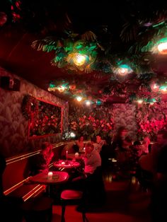 people sitting at tables in a dimly lit room with plants on the walls and ceiling