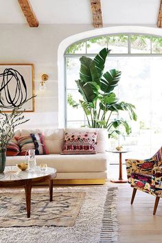 a living room filled with furniture next to a large open window and potted plant