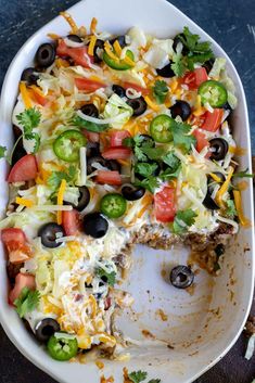 a white plate topped with a taco salad covered in cheese and black olives