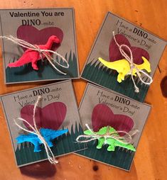 three valentine's day cards with dinosaurs tied to them on a wooden table