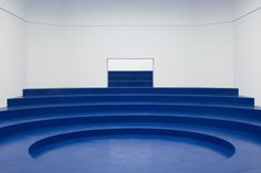 an empty room with blue steps leading up to the ceiling and white walls behind it