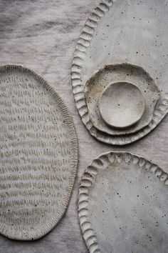 three plates and one bowl are sitting on a tablecloth with white circles around them