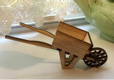 a wooden toy horse pulling a cart on wheels next to a vase and window sill