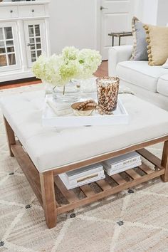 a living room filled with furniture and flowers on top of a coffee table in front of a fireplace