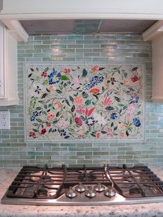 a stove top oven sitting inside of a kitchen next to a wall with flowers on it