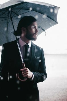 a man in a suit and tie holding an umbrella