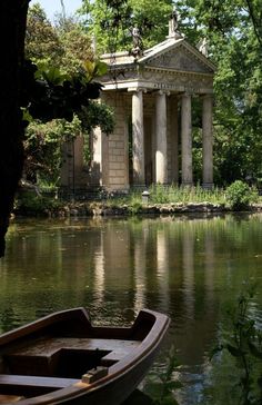 there is a boat on the water in front of a building with columns and pillars