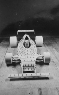 an old photo of a race car on the ground with wheels attached to it's rear end