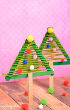 two small christmas trees made out of popsicle sticks with pom - poms