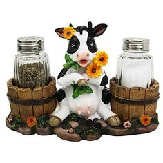 a cow with sunflowers sitting in front of two salt and pepper shakers