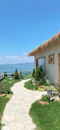 a pathway leading to a house on the beach with thatched roof and grass roofs