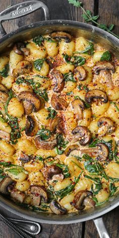 a pan filled with potatoes and mushrooms on top of a wooden table