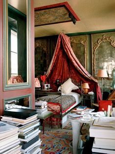 a bedroom with a canopy bed and lots of books on the floor in front of it