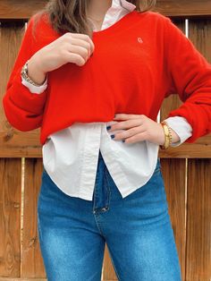 a woman in jeans and a red sweater is posing for the camera with her hands on her hips