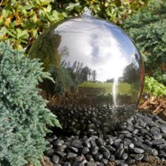 a large metal ball sitting in the middle of a garden