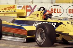 a man driving a yellow race car on top of a track