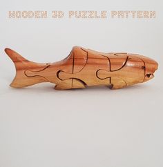 a wooden puzzle piece shaped like a fish sitting on top of a white surface with the words wooden 3d puzzle pattern below it