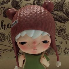 a little doll with a big hat on her head is standing in front of a wall