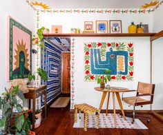 a living room filled with furniture and paintings on the wall next to a wooden floor