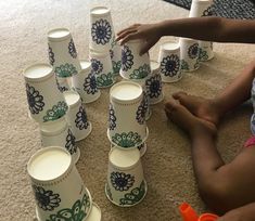 a person sitting on the floor next to many cups