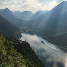 a large body of water surrounded by lush green hills and trees on both sides of the river