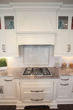 a kitchen with white cabinets and marble counter tops, along with an oven in the center