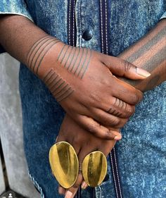 a person with tattoos on their arms holding onto two gold rings