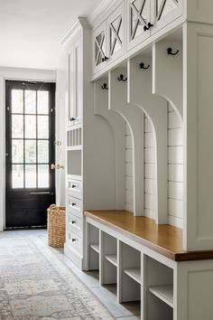 a white entryway with built - in benches and shelves