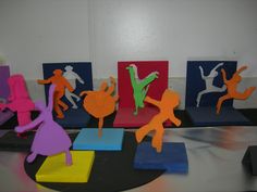 several different colored paper sculptures on display in front of a white wall and black table