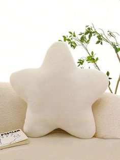 a white star shaped pillow sitting on top of a couch next to a small book