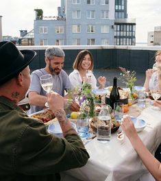 a group of people sitting around a table with food and drinks on top of it