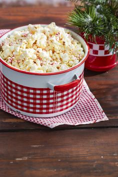 a red and white bowl filled with popcorn sitting on top of a wooden table