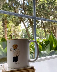 a coffee cup sitting on top of a stack of books in front of a window