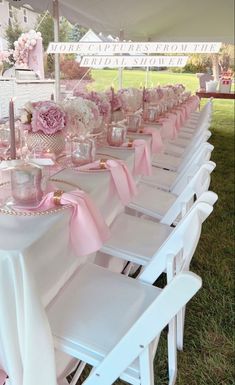 there are many white chairs and tables with pink napkins on them at this outdoor event