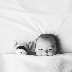 a black and white photo of a baby with a stuffed animal