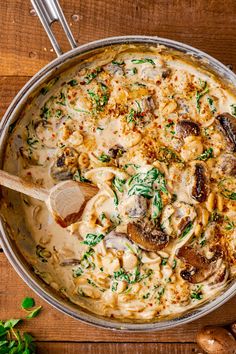 a pan filled with pasta and mushrooms on top of a wooden table