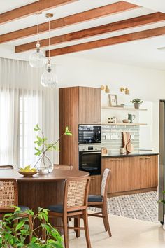 an open kitchen and dining room area with wood beams in the ceiling, white curtains on the windows