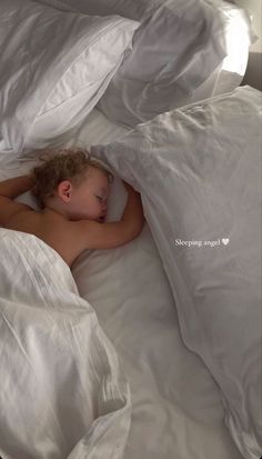 a small child is sleeping in a bed with white sheets and pillows on it's sides