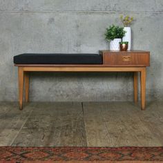 a wooden bench sitting on top of a hard wood floor next to a potted plant