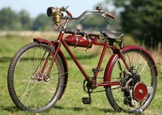 an old red bicycle is parked in the grass