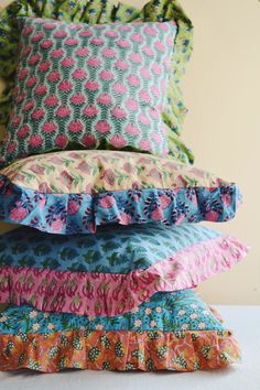 four pillows stacked on top of each other with ruffles in different colors and patterns