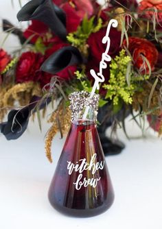 a vase filled with red flowers on top of a white table next to a bouquet