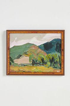 a painting hanging on the wall in front of a white wall with a wooden frame