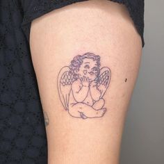 an angel tattoo on the leg of a woman's left thigh, with her hands clasped to her chest