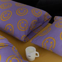 a coffee cup sitting on top of a bed next to two pillows and a pillow case