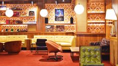 a living room filled with lots of furniture and wooden paneled wall mounted bookshelves