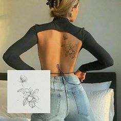 a woman with tattoos on her back standing in front of a bed